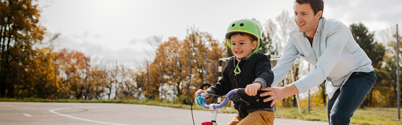 dad helping son to ride a bike